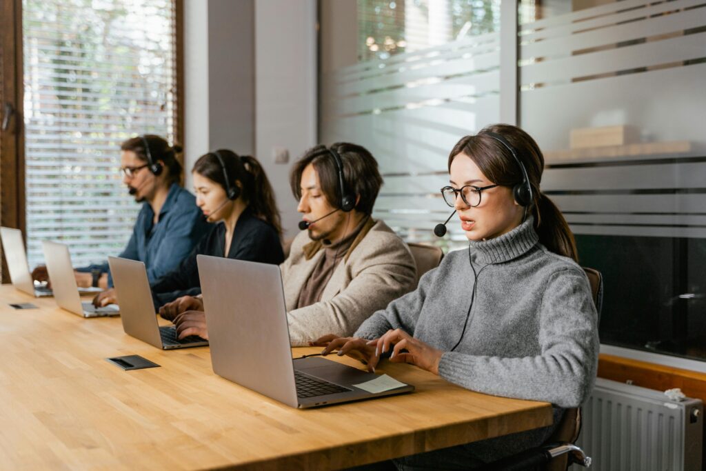 pexels-photo-7709157-7709157 Call center team working at laptops with headsets, providing customer support.