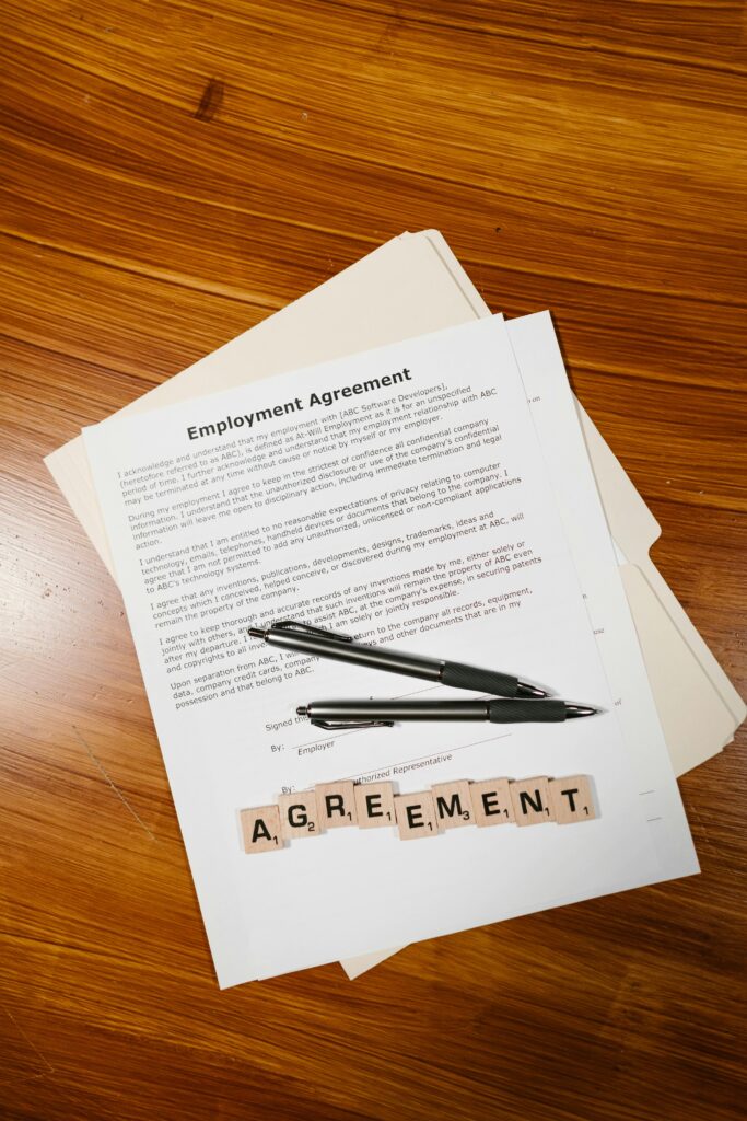 pexels-photo-7841413-7841413 Employment agreement with Scrabble tiles spelling 'AGREEMENT' on wooden surface, captured in detail.